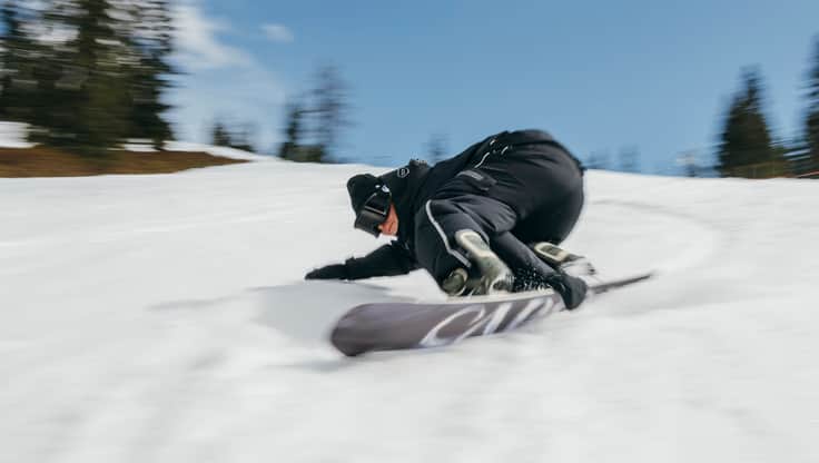 Two friends carving with snowboards on the slopes