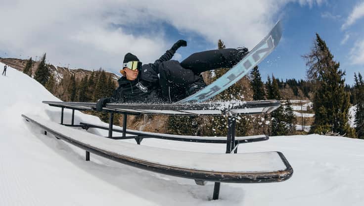 Freestyle snowboarder doing a trick on a box in the snowpark, with a soft board