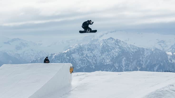 Snowboarder jumps over a large rock