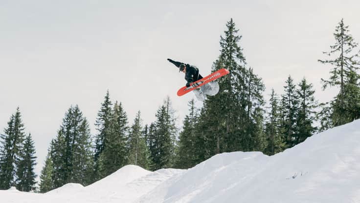 Snowboarder jumps over a large rock