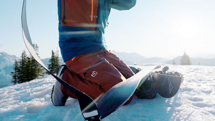 Deux splitboardeurs appliquant des peaux sur leurs boards avant une randonnée