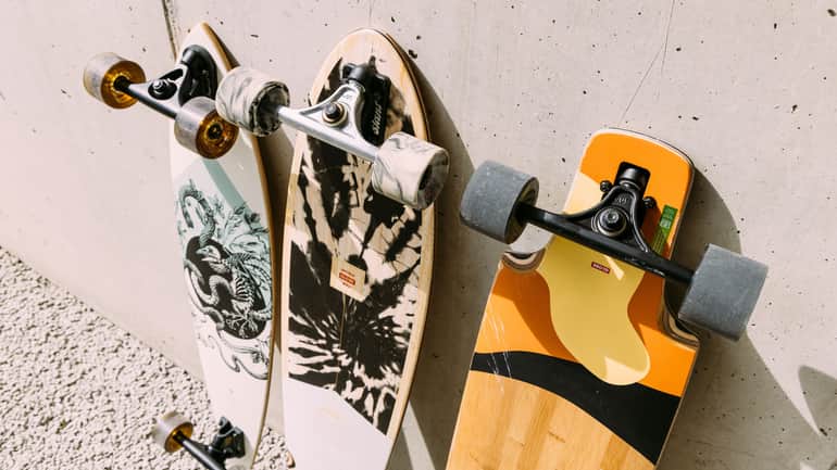 Unterschiedliche Cruiser und Longboards vor einer Wand