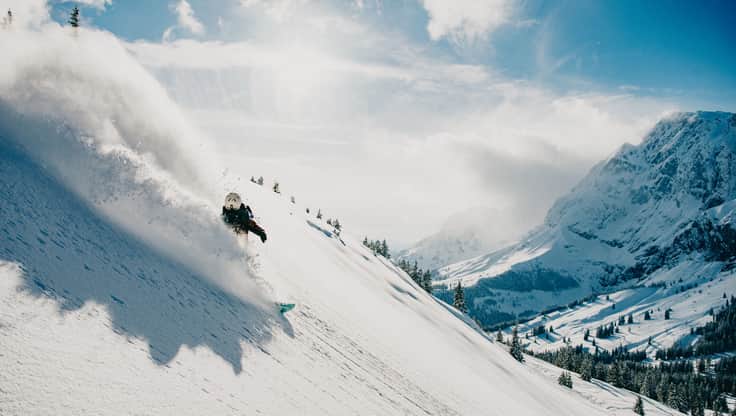 Freeride snowboarder riding a steep mountain