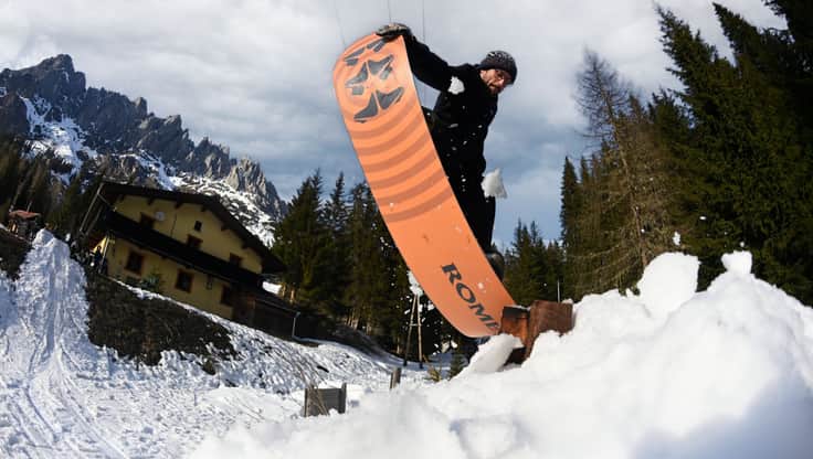 Freestyle snowboarder doing a trick on a box in the snowpark, with a soft board